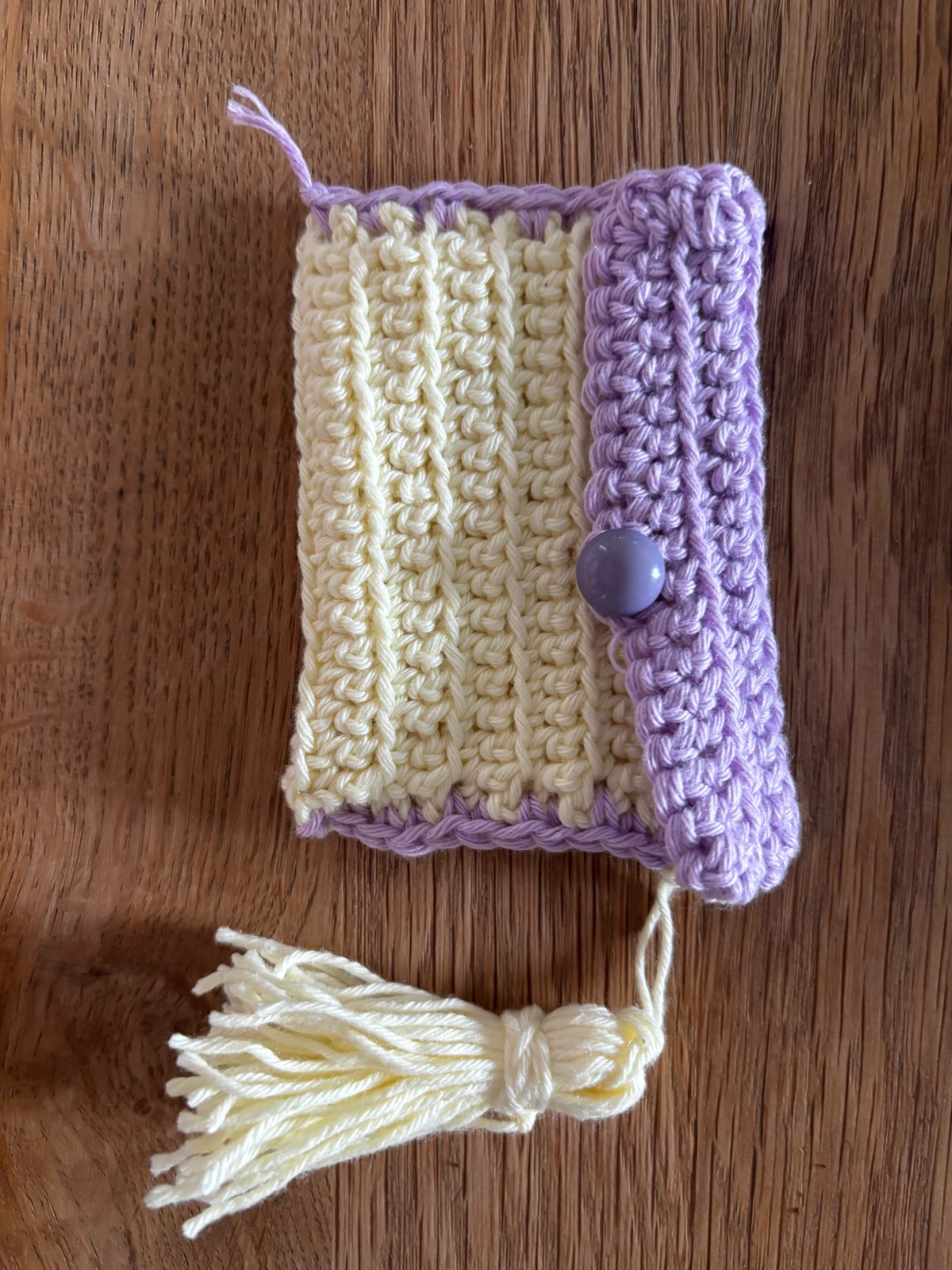 The finished mini pouch — cream ribbed body, lavender flap with a button, and a tassel